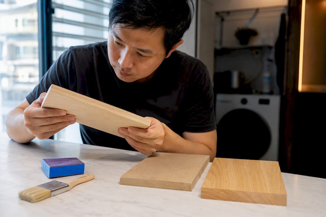 Asian DIYer comparing woodworking material samples