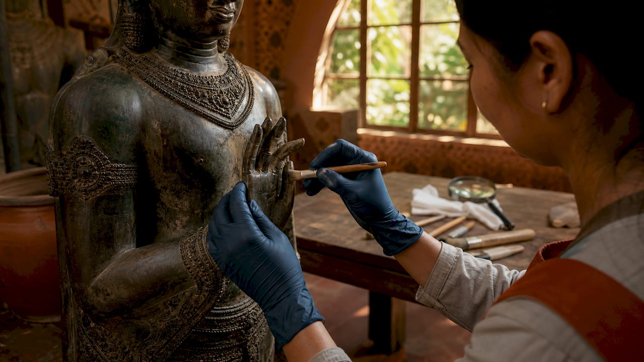Hands cleaning bronze Khmer statue detail