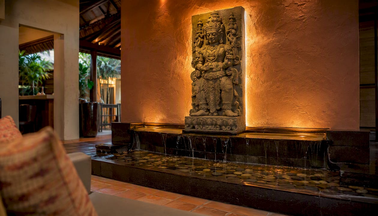 Stone temple relief above water feature in lobby corner
