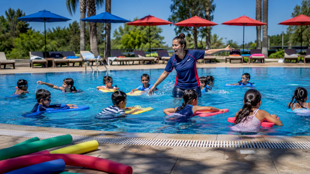 Overcrowded children swim class with distracted instructor