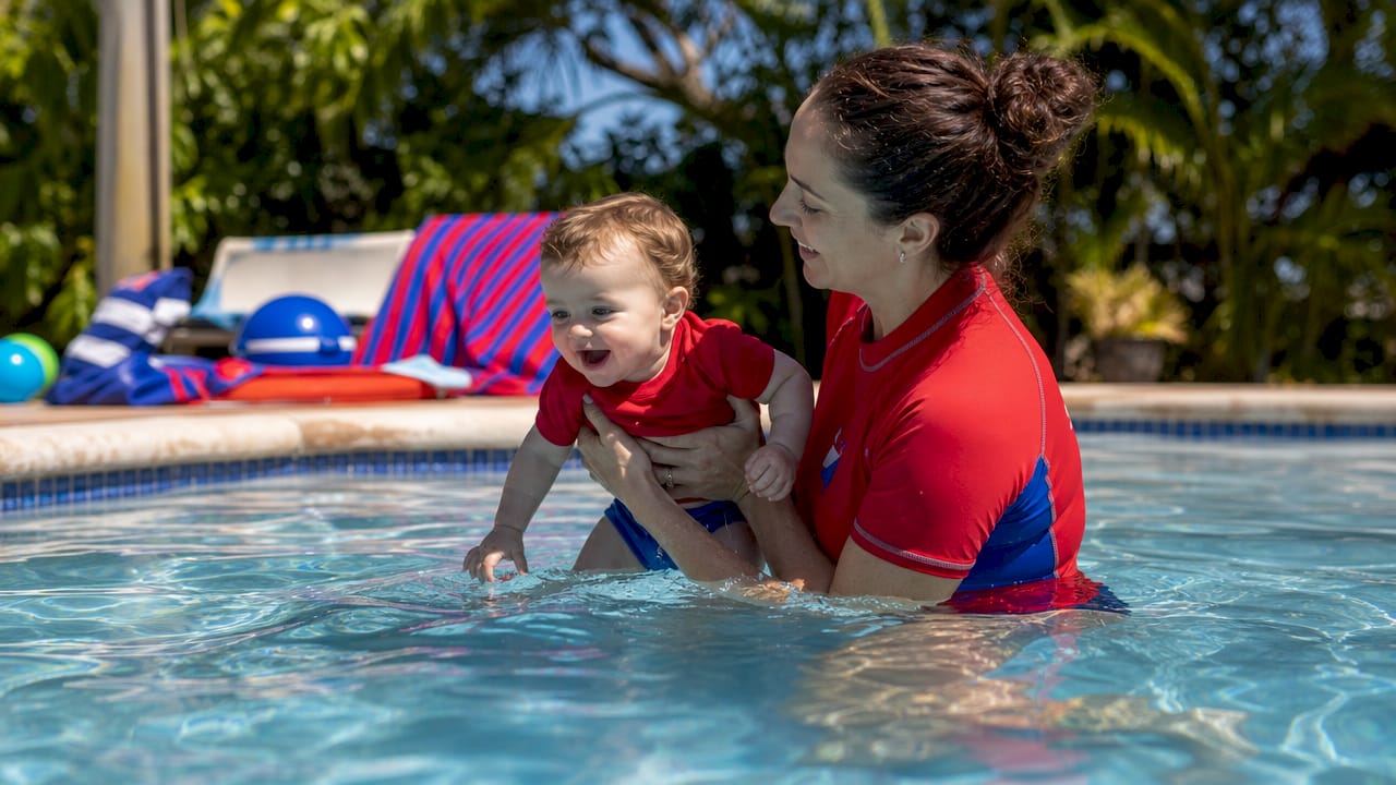 Instructor holding infant safely in pool water