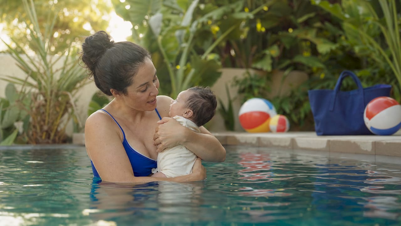 Mother calmly holding infant in swimming pool