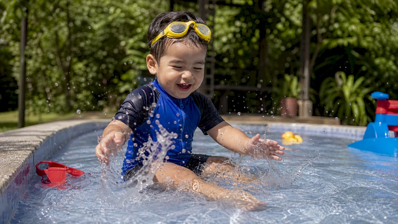 Toddler splashing water during swim lesson