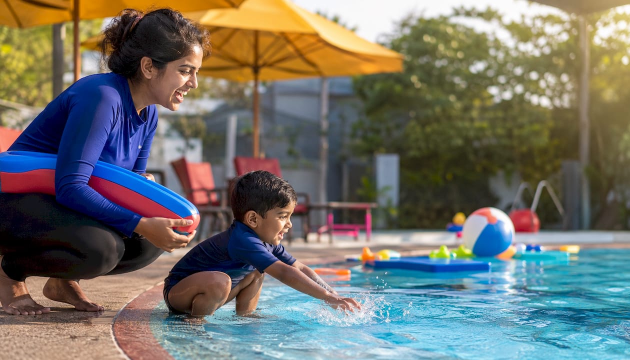 Mother and toddler at pool edge preparing swim