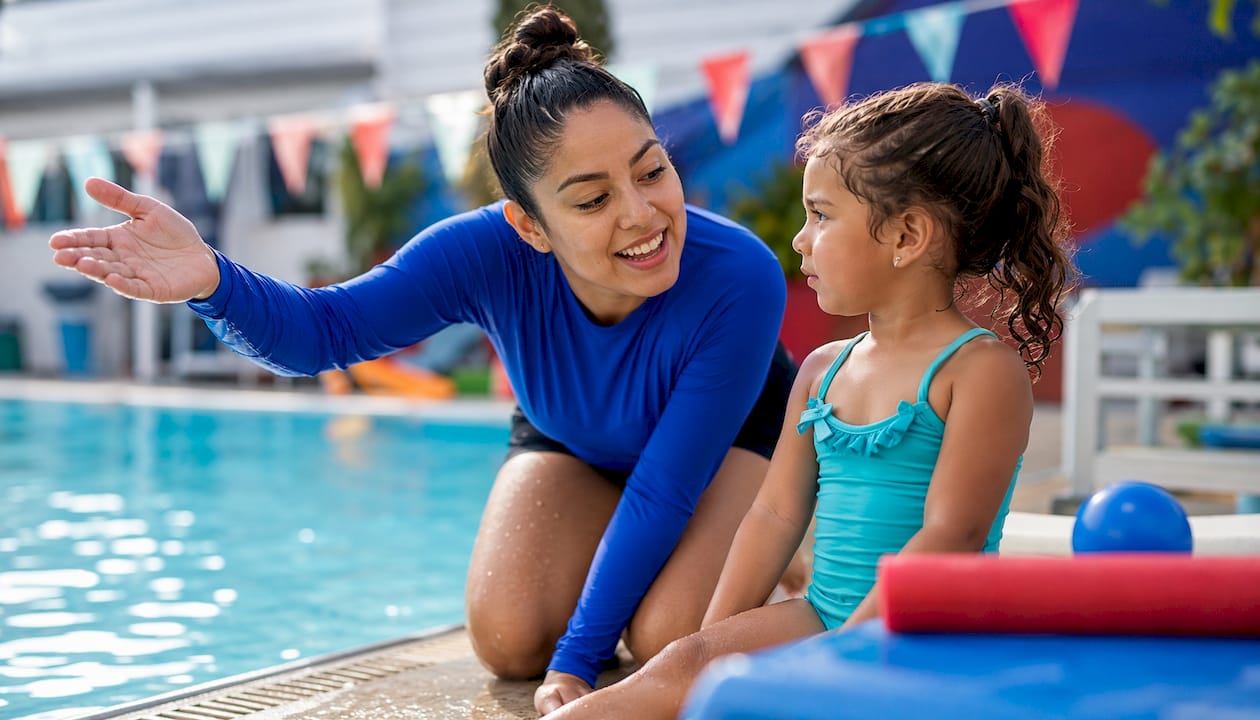 Swim instructor teaching young child outdoors