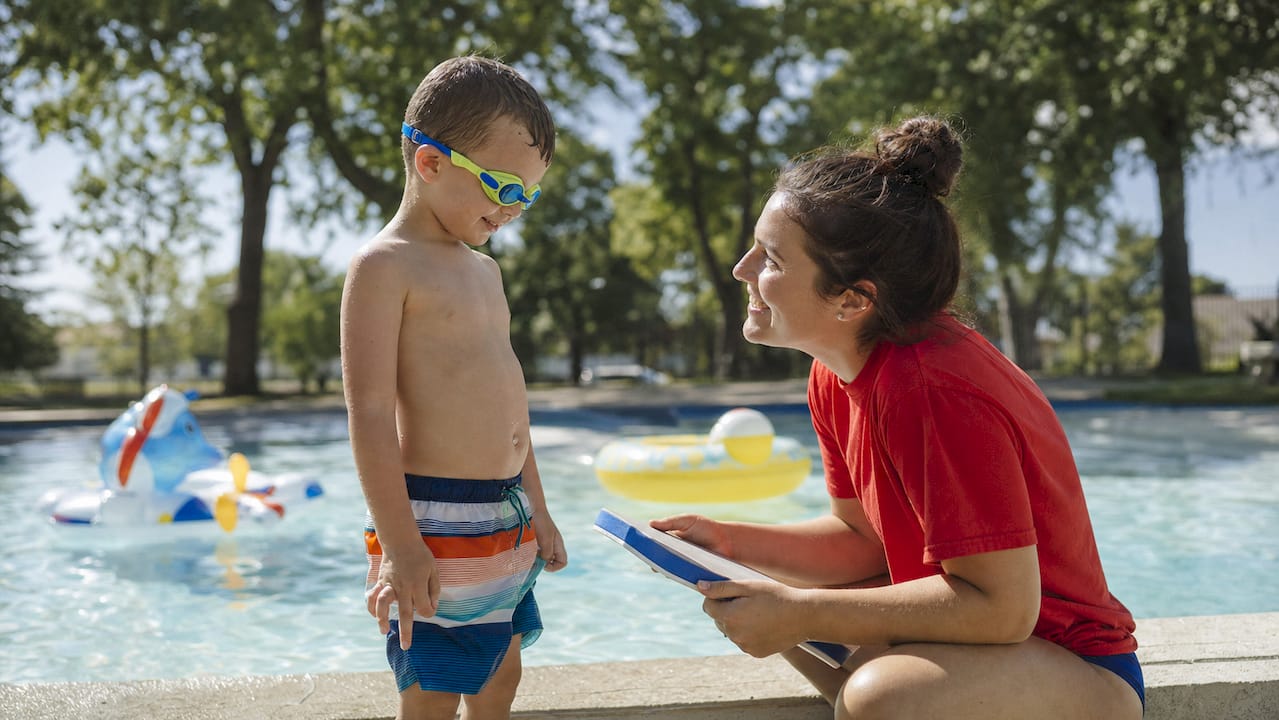 Child and instructor at swim lesson pool edge