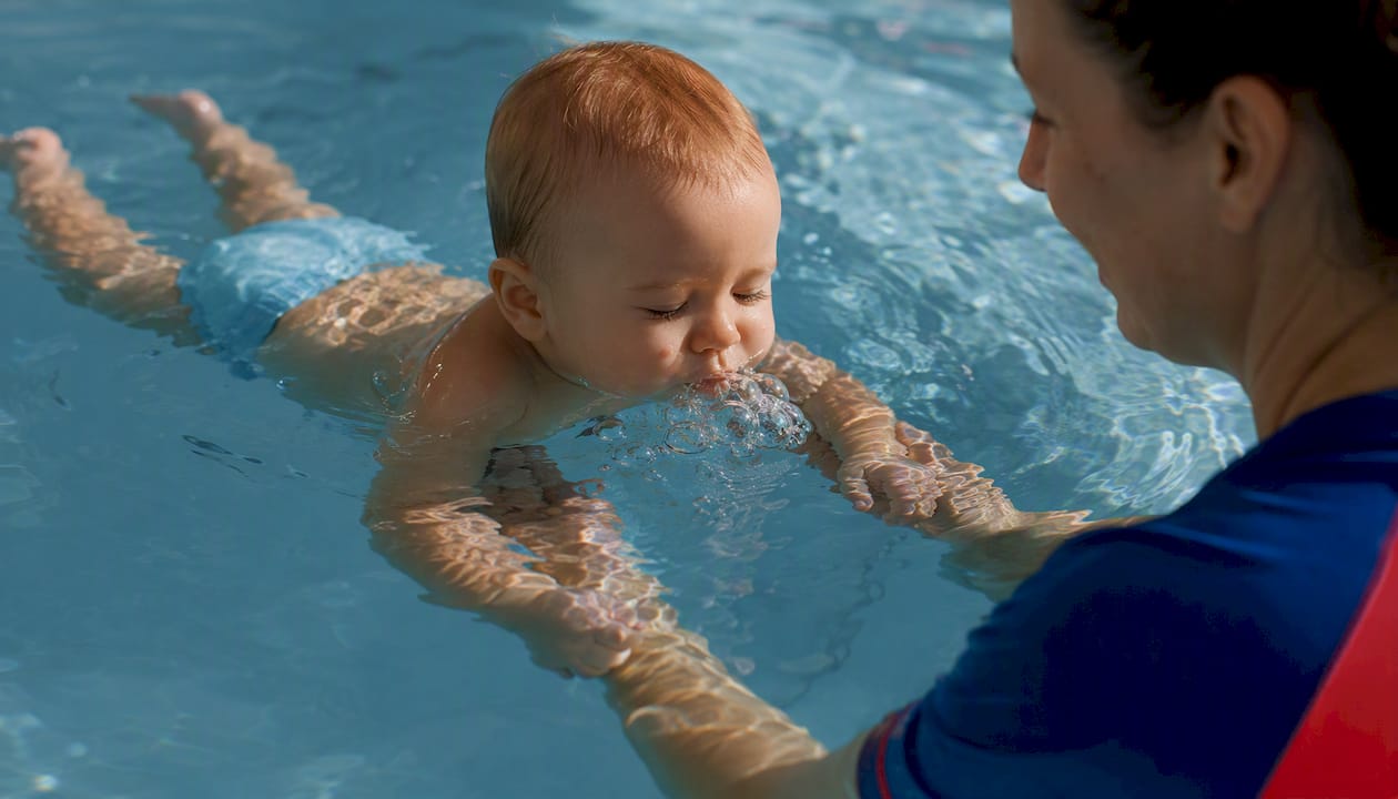 Infant blowing bubbles underwater in swim lesson