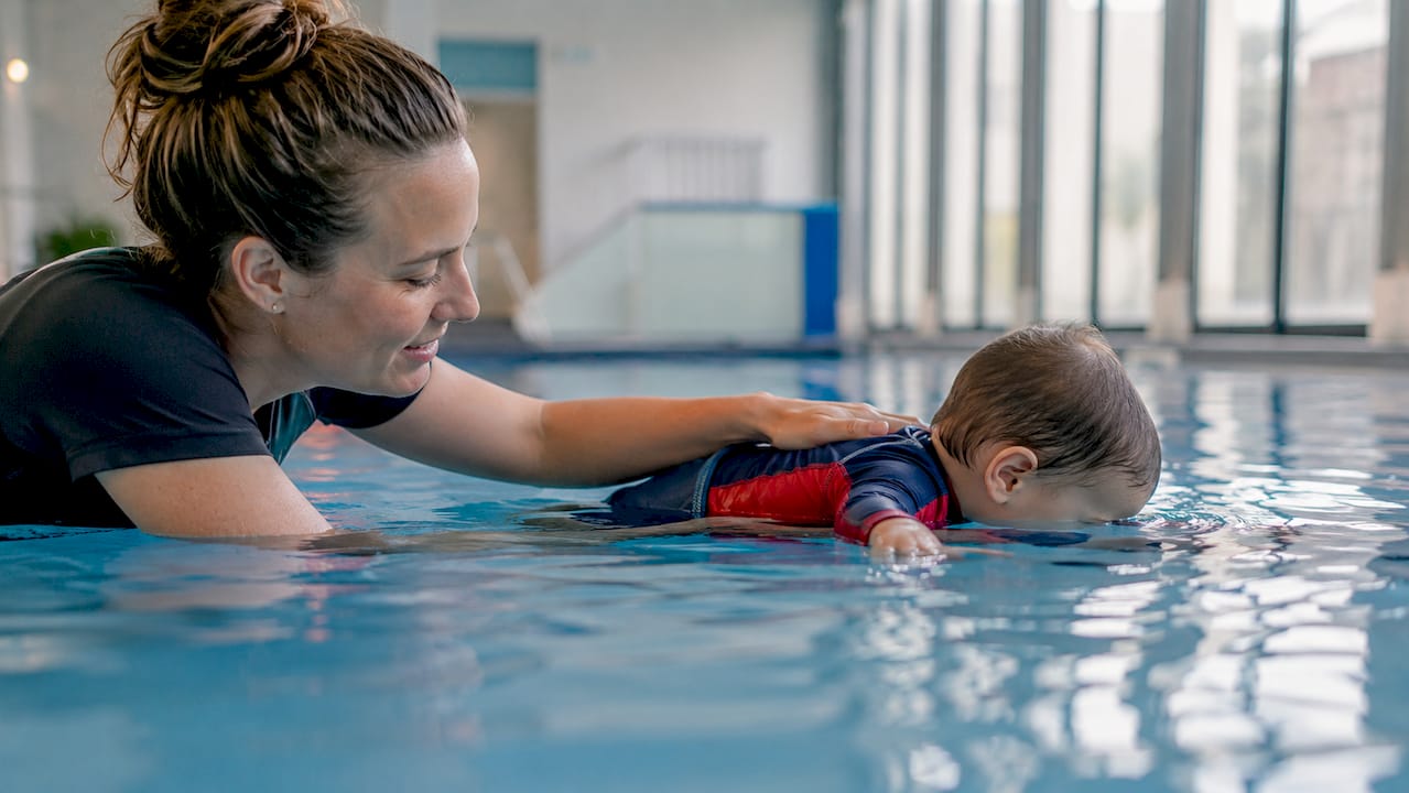 Instructor supporting anxious toddler in swim lesson
