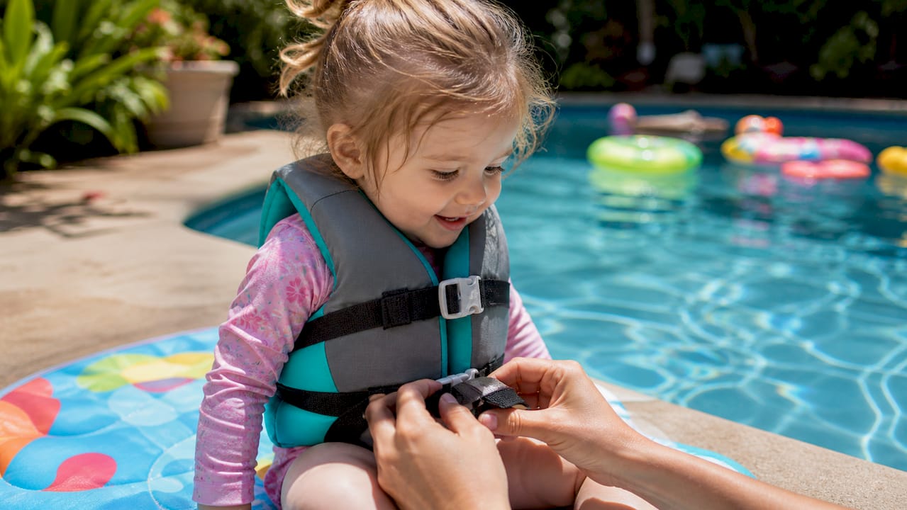 Toddler fitted with USCG-approved life jacket poolside