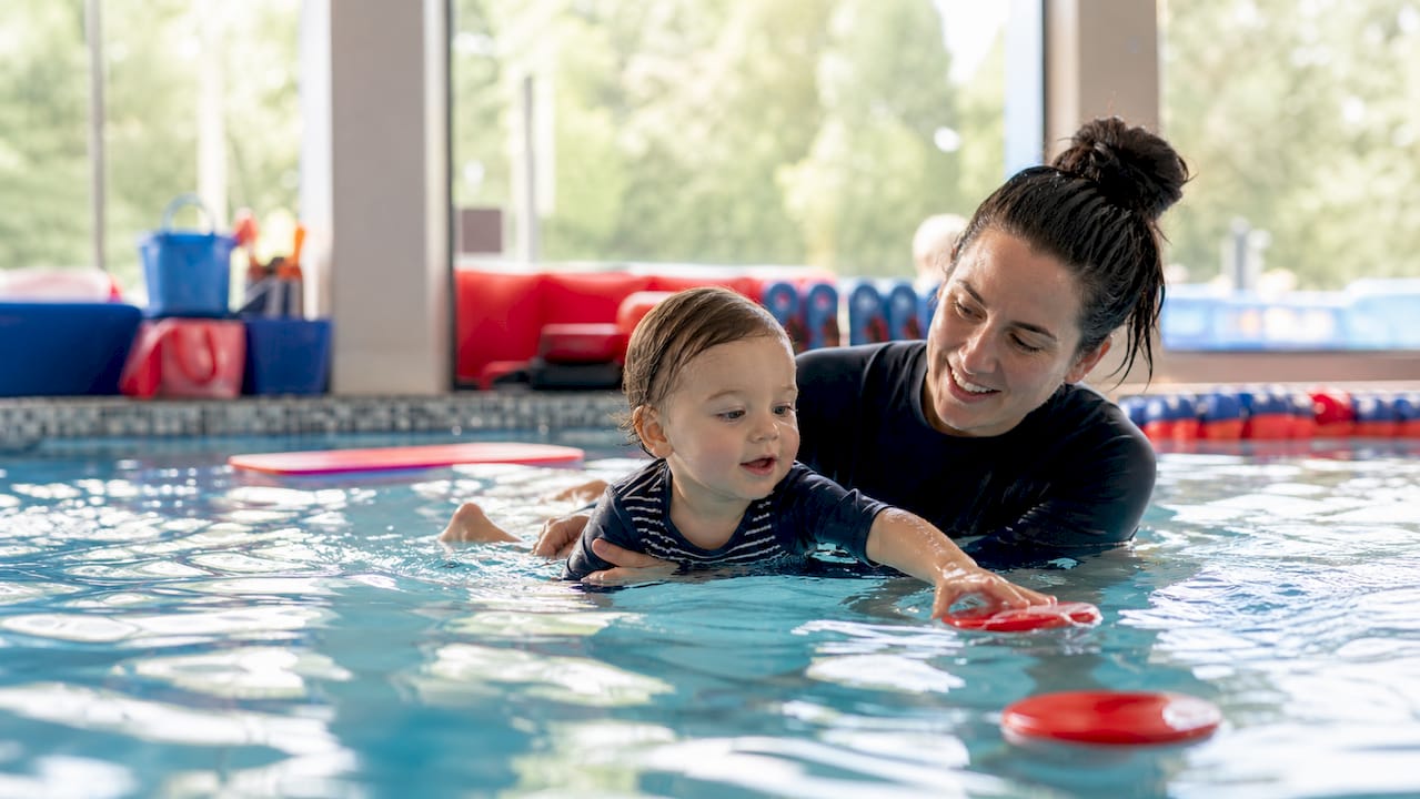 Instructor supporting toddler in swim lesson