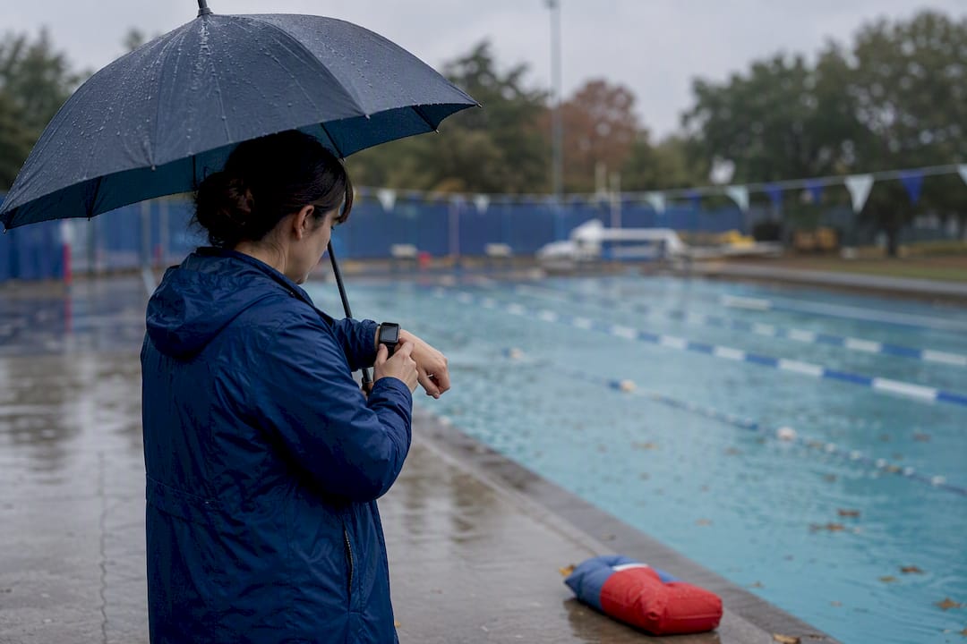 Parent checking swim lesson cancellation outdoors on rainy day