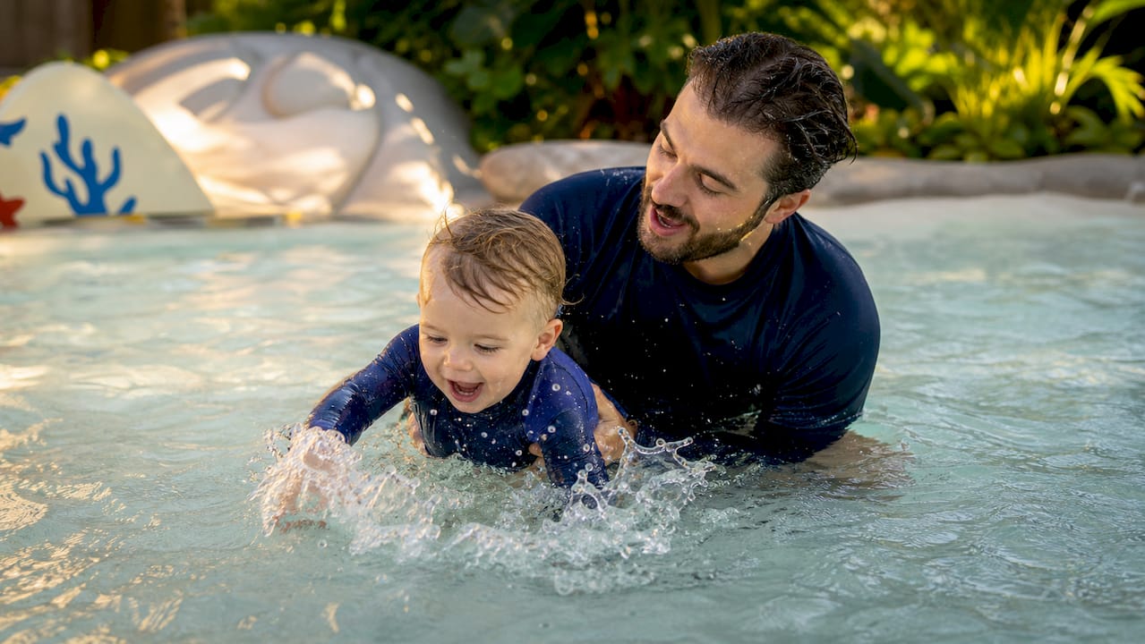 Instructor playfully teaching toddler survival swim skills