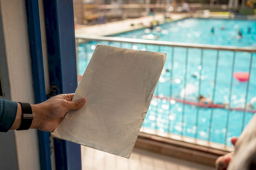 Instructor holding insurance certificate near pool