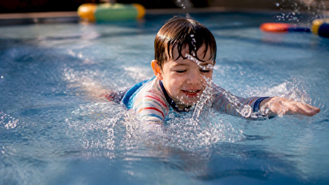 Child swimming in clothes in outdoor pool