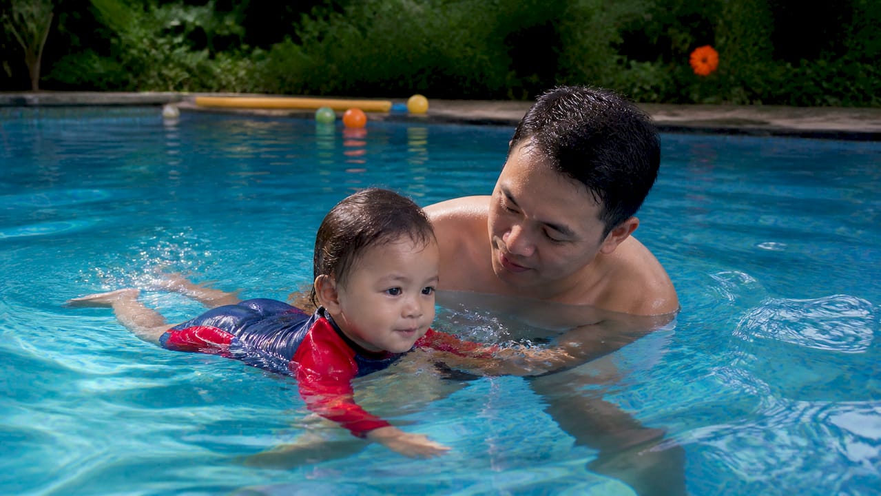 Parent supporting toddler during private swim lesson