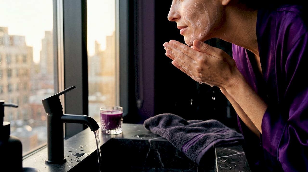 Hands rinsing cleanser off face