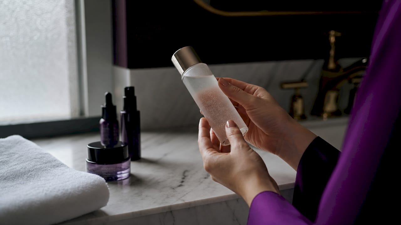 Hands holding exfoliating toner bottle