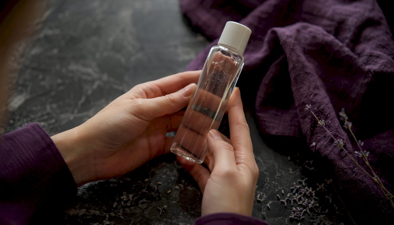 Close-up of hands examining skincare ingredient label