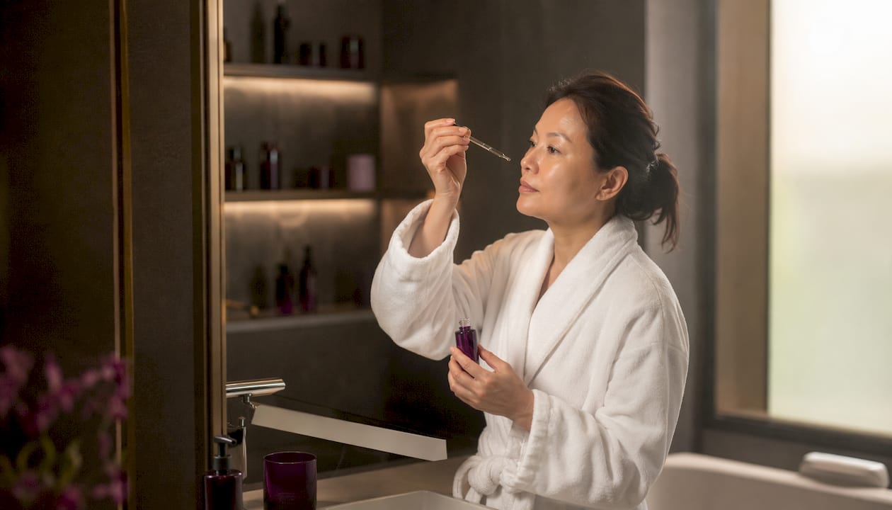 Woman applying Sulwhasoo serum in bathroom