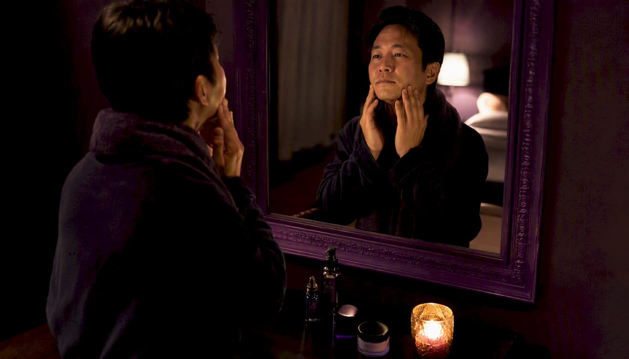 Man performing facial massage in bathroom