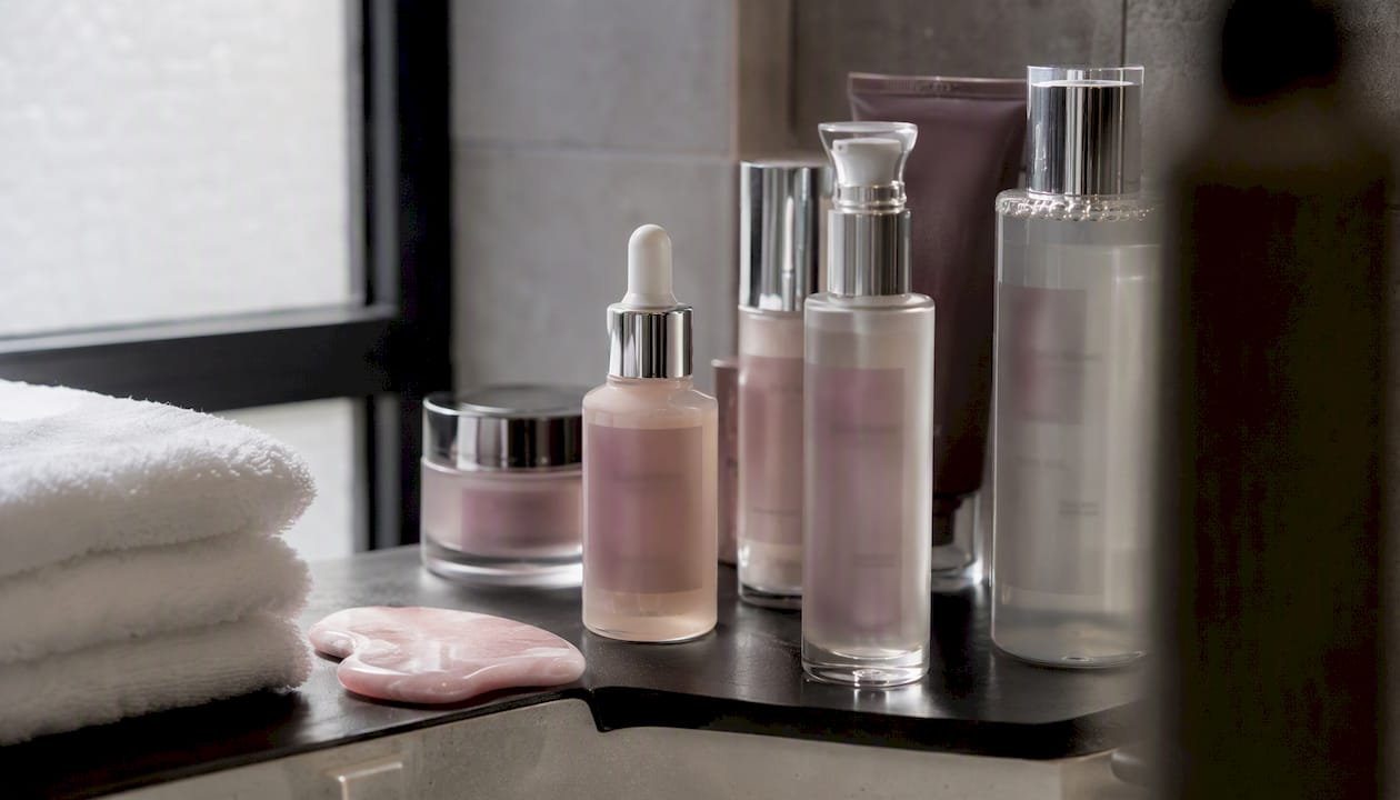 Skincare bottles and tools on bathroom shelf
