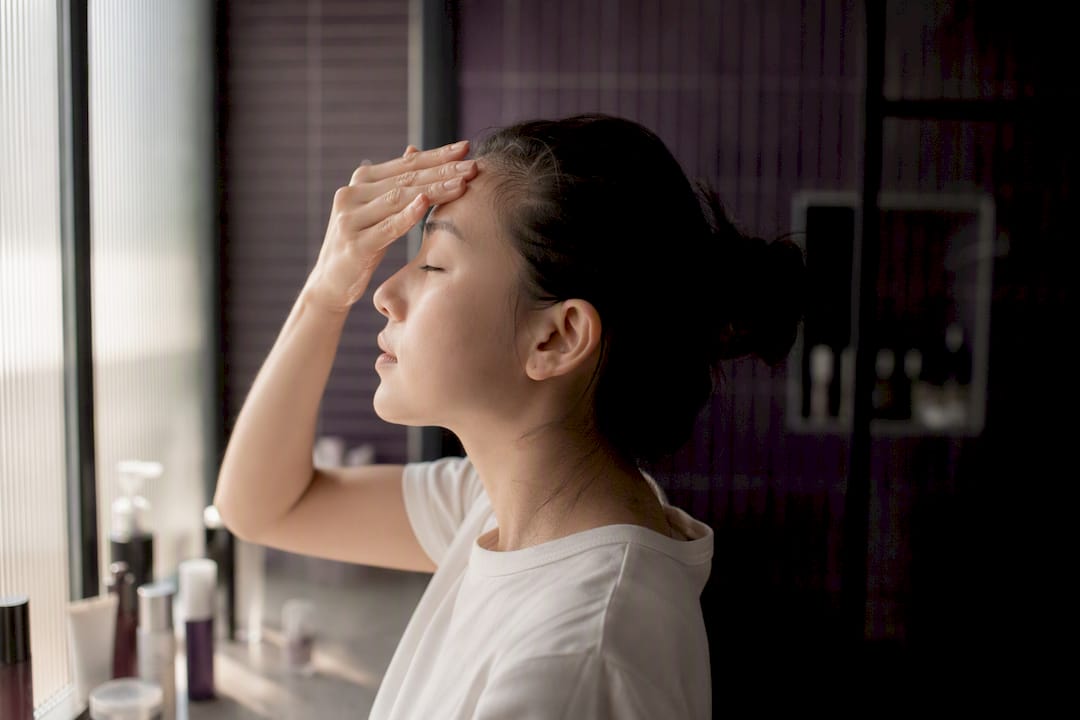 Hands applying Korean skincare serum on face
