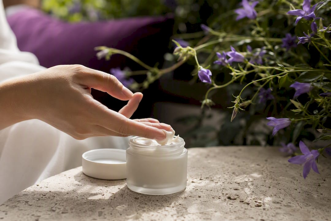 Hand scooping light moisturizer from jar