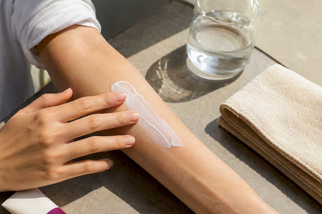 Hand applying mineral sunscreen outdoors