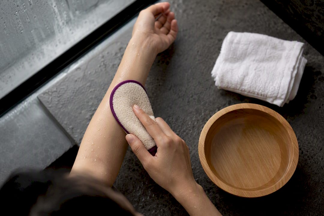 Hands gently exfoliating a forearm with mitt