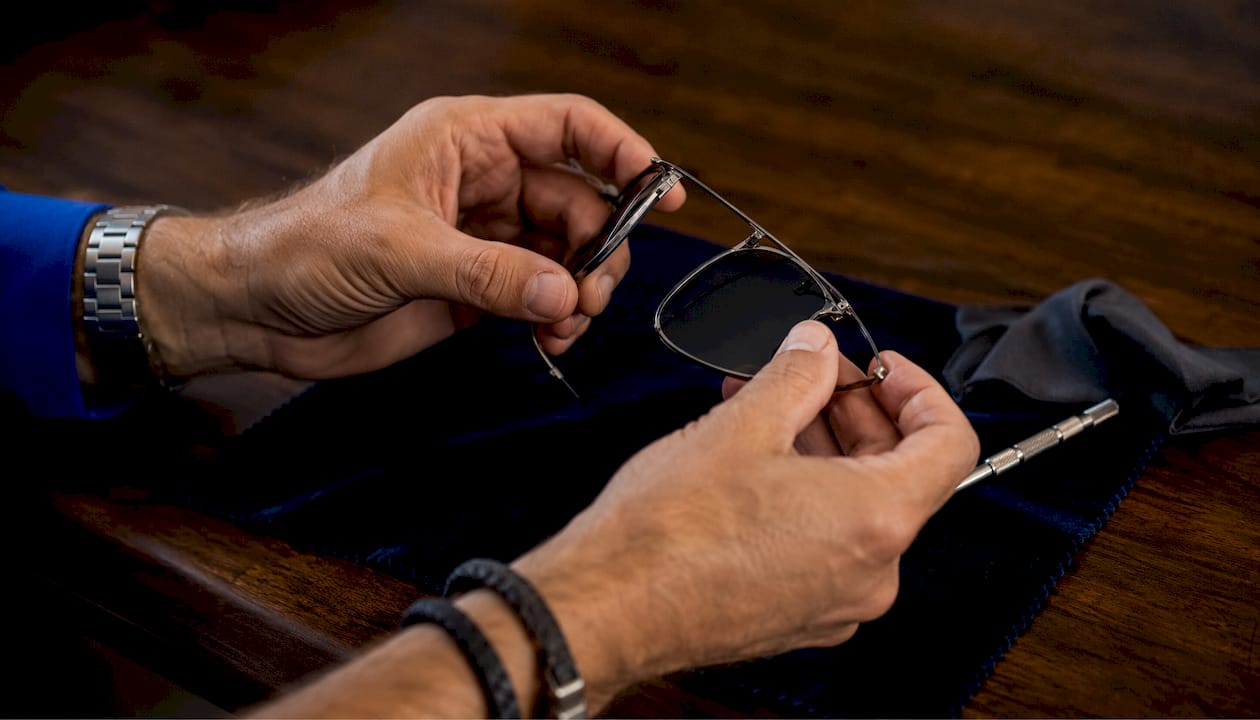 Adult hands bending titanium aviator sunglasses on table