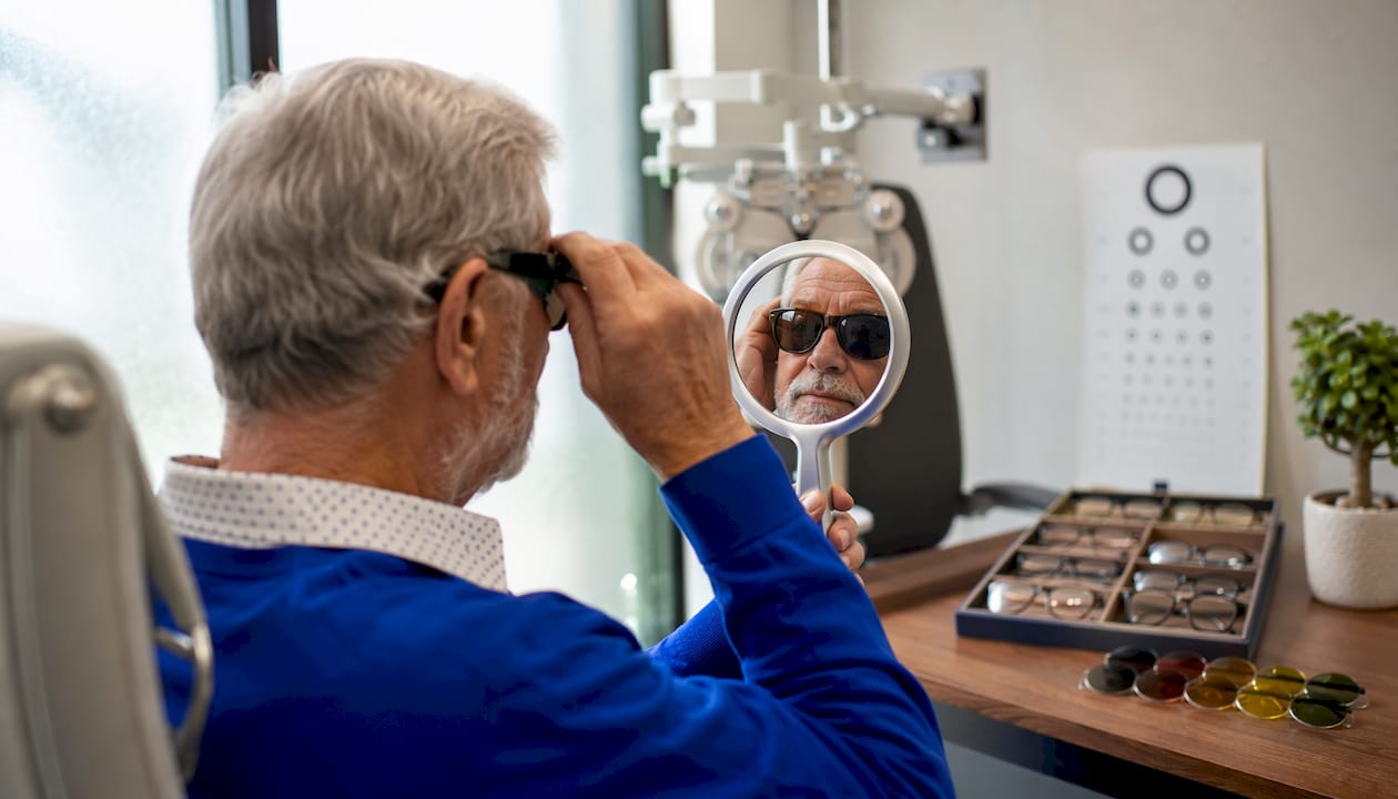 Man adjusting fit-over sunglasses indoors