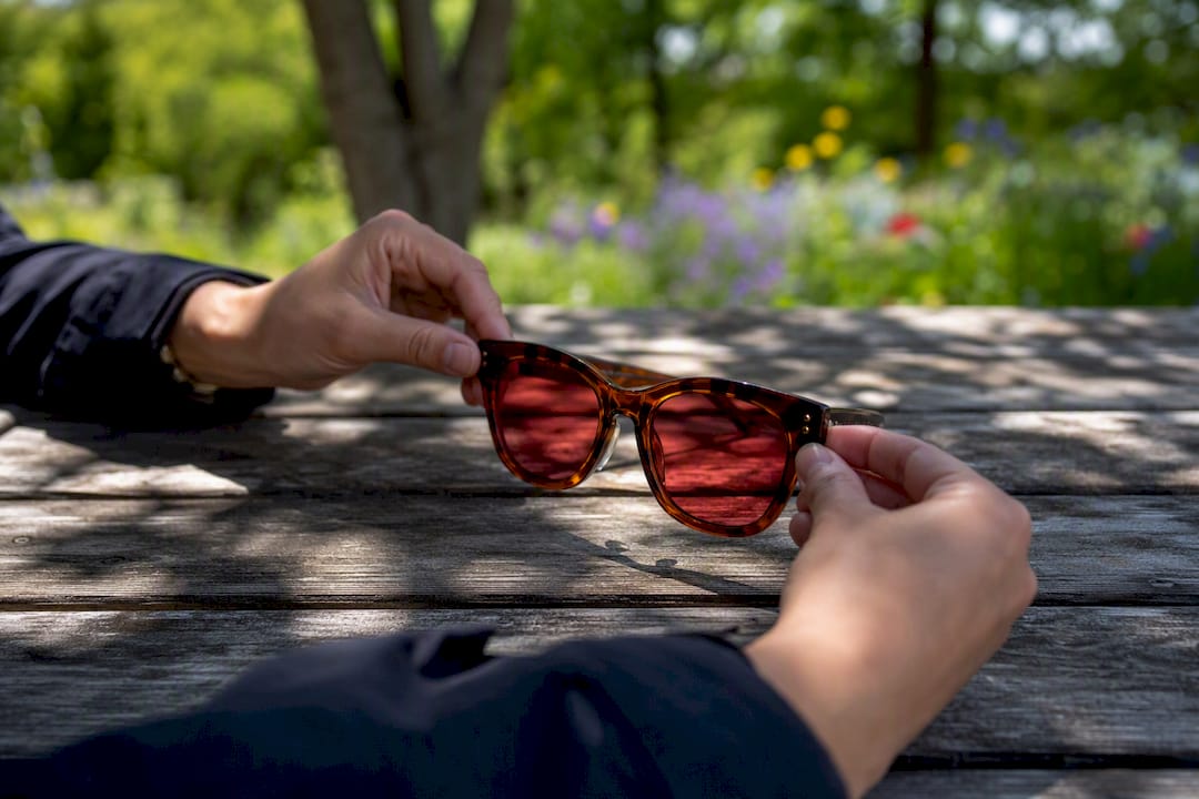 Hands adjusting color tinted acetate sunglasses