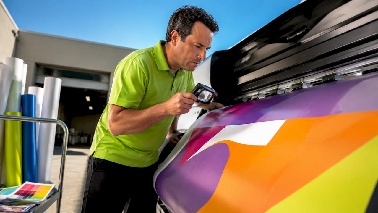 Print technician inspecting booth graphic on printer