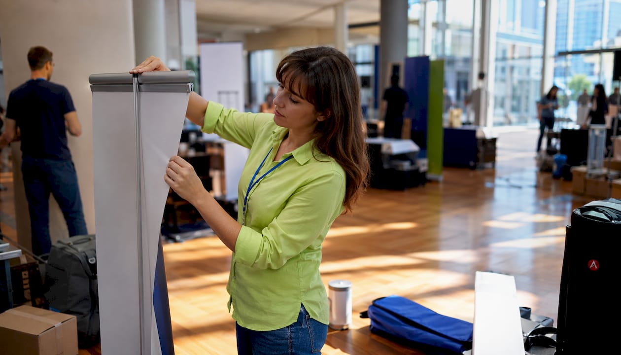 Female assembling retractable banner stand outdoors