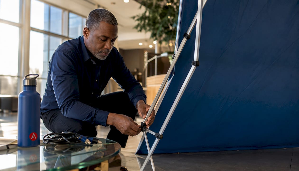 Man assembling fabric backwall in conference room