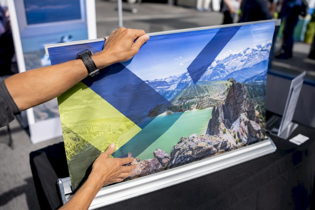 Hands attaching printed fabric to booth frame