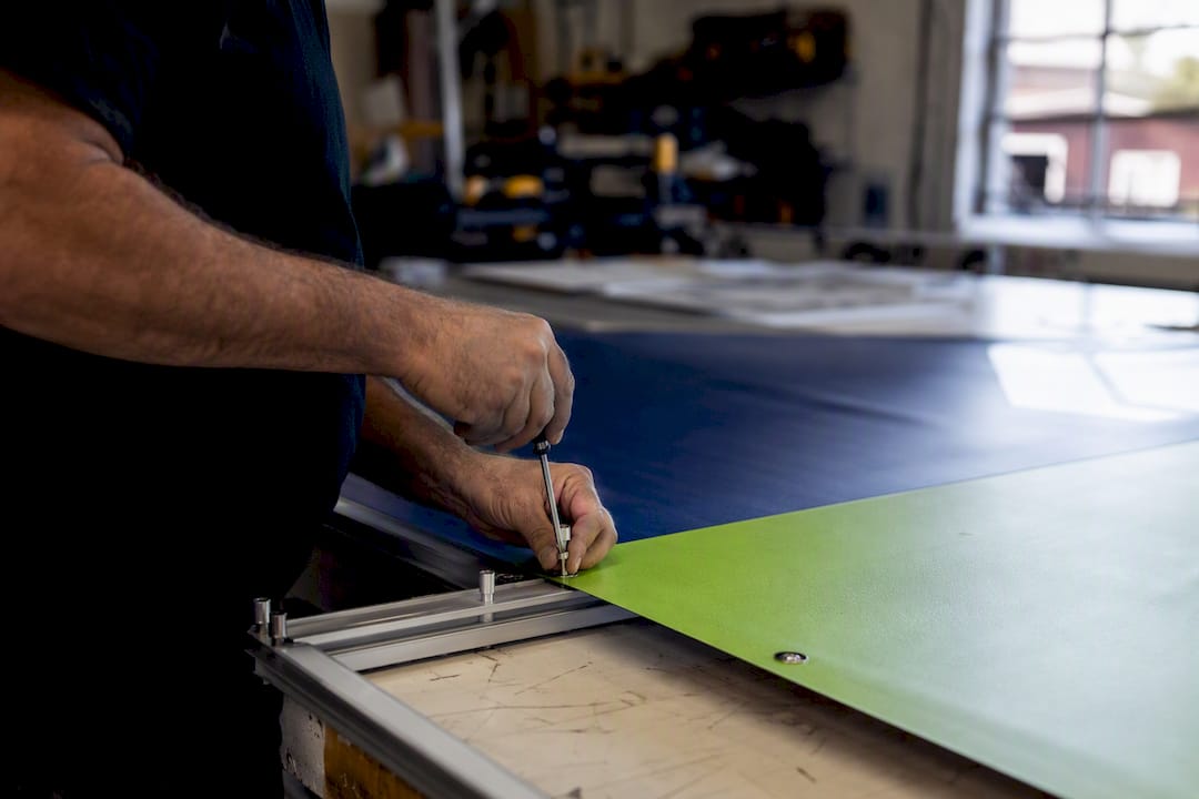 Hands installing mounting hardware on signage frame