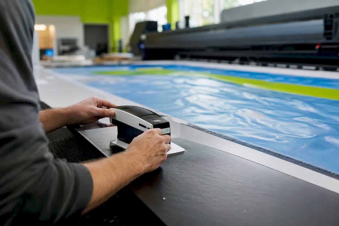 Hands calibrating color device on printed banner