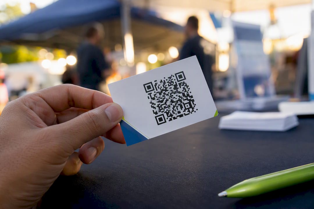 Hand holding business card with visible QR code