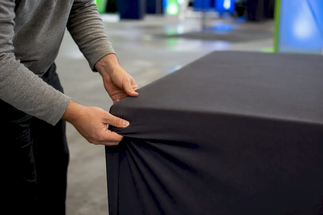 Hands installing fabric table cover on trade show table