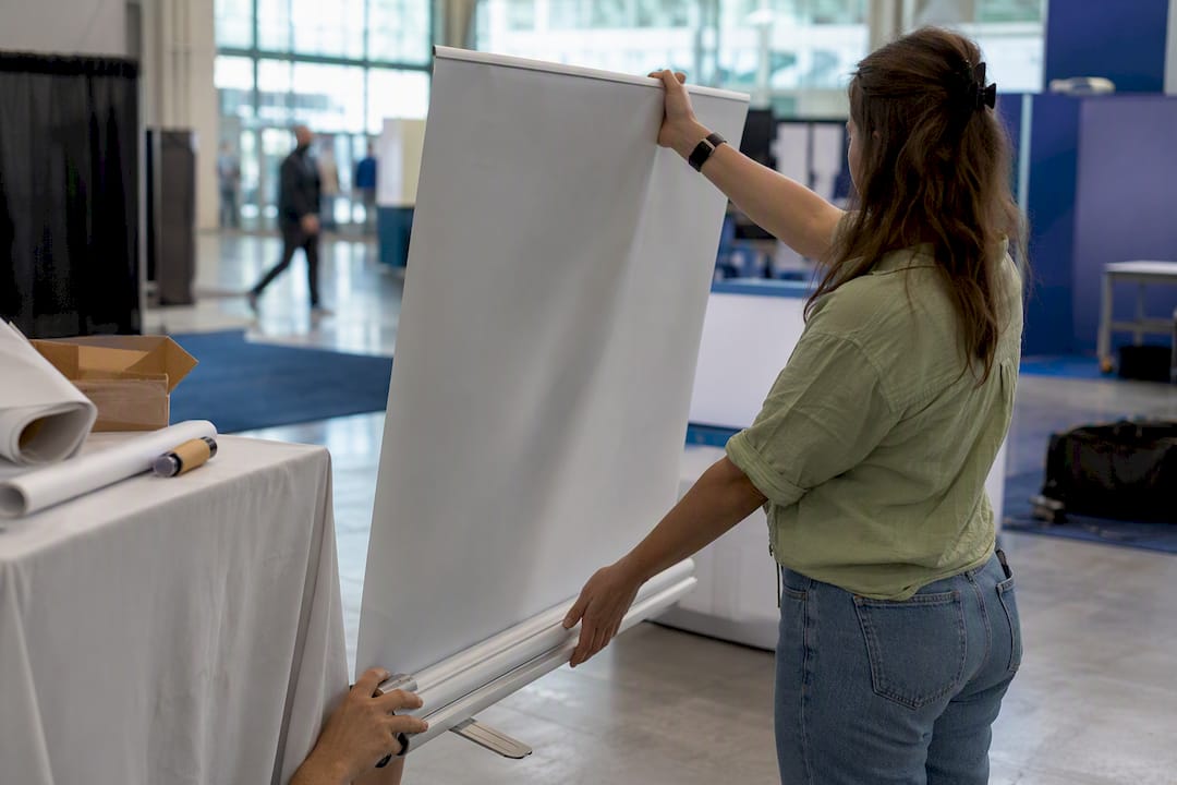 Hands assembling retractable banner stand at event