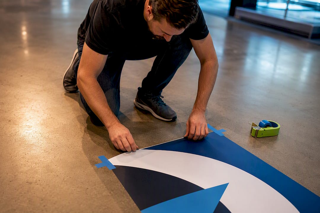 Hands aligning a trade show floor decal