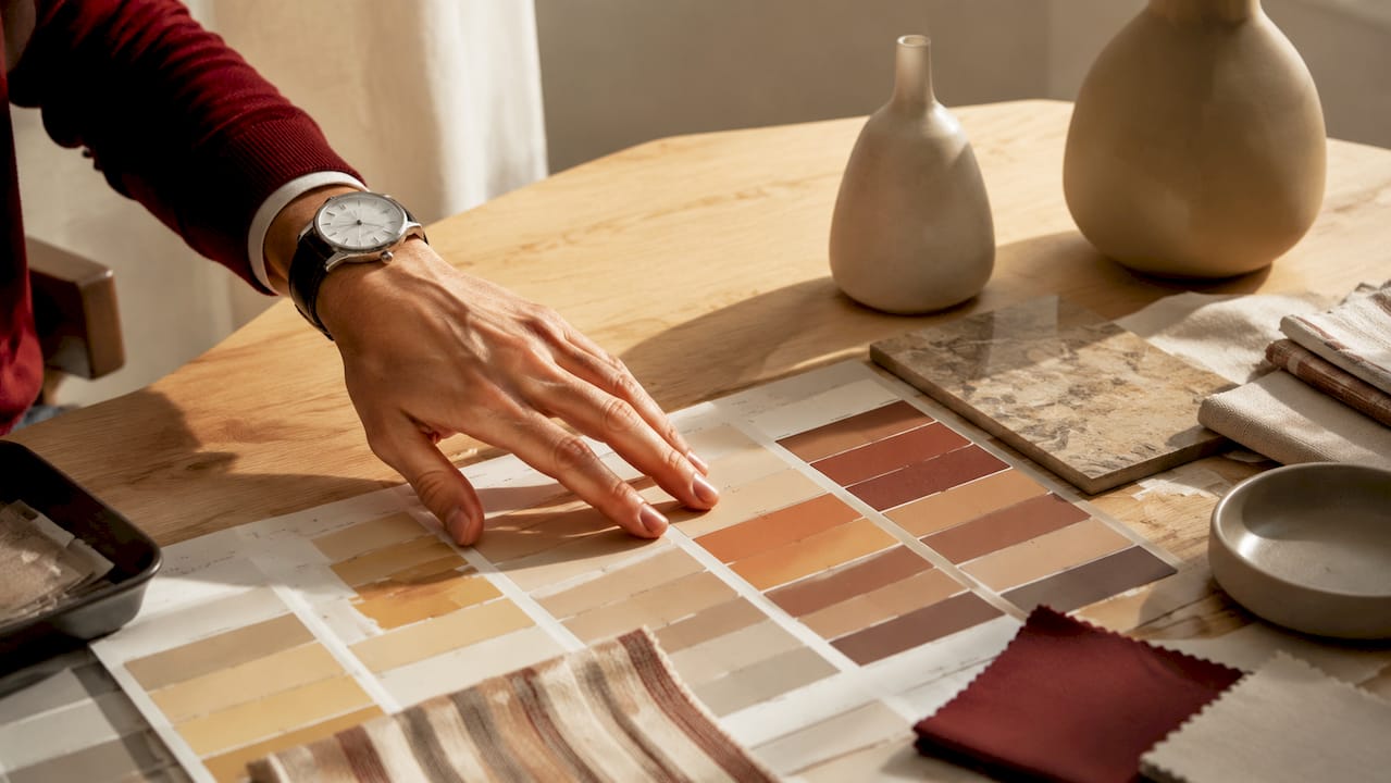 Una mano che seleziona campioni di colori e tessuti disposti su un tavolo