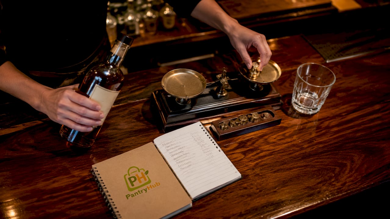 Hands weighing liquor bottle on digital scale