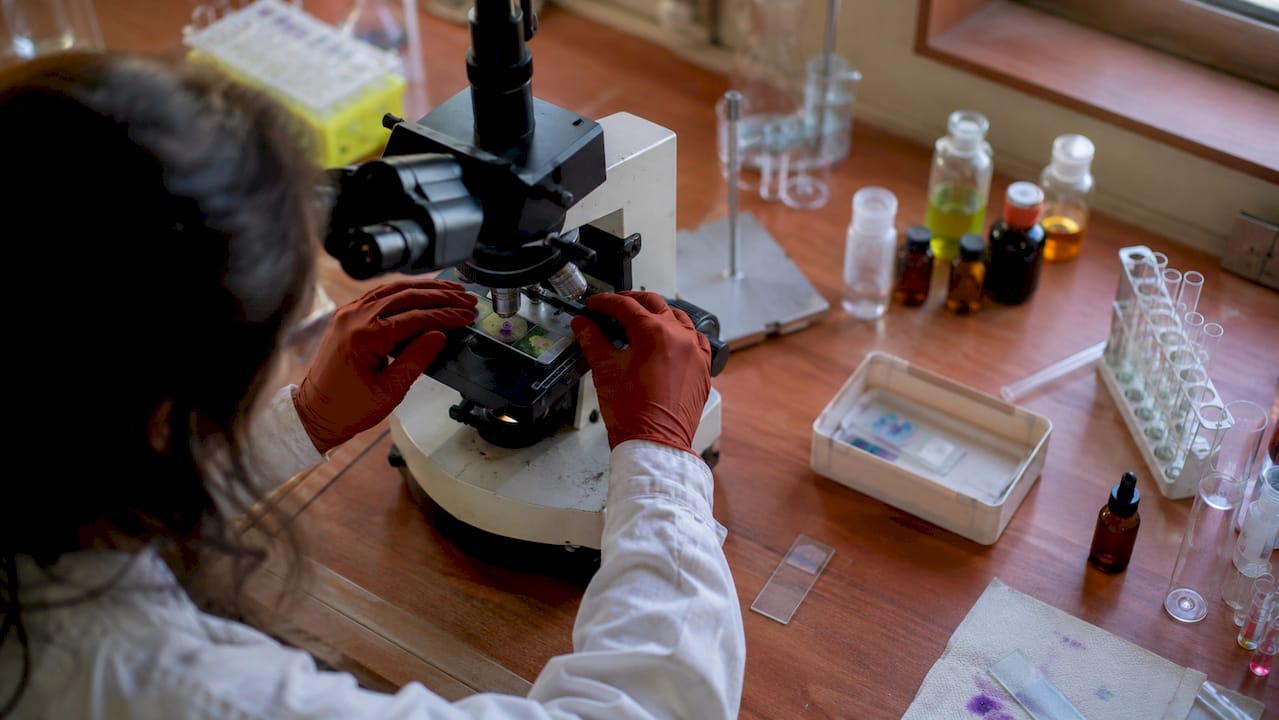 Scientist examining cellular slide under microscope