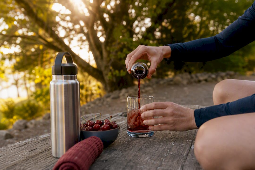 Hands pouring tart cherry concentrate supplement
