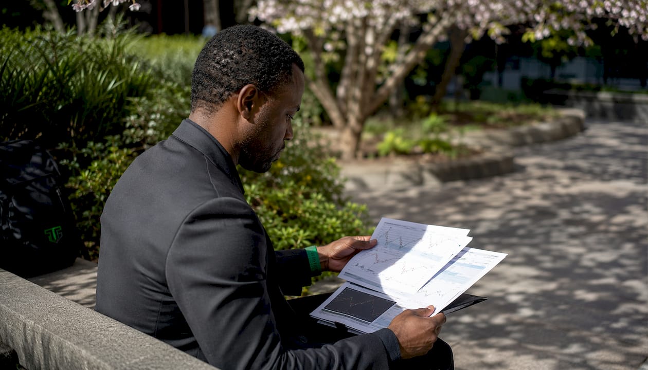 Trader reviewing forex charts on park bench