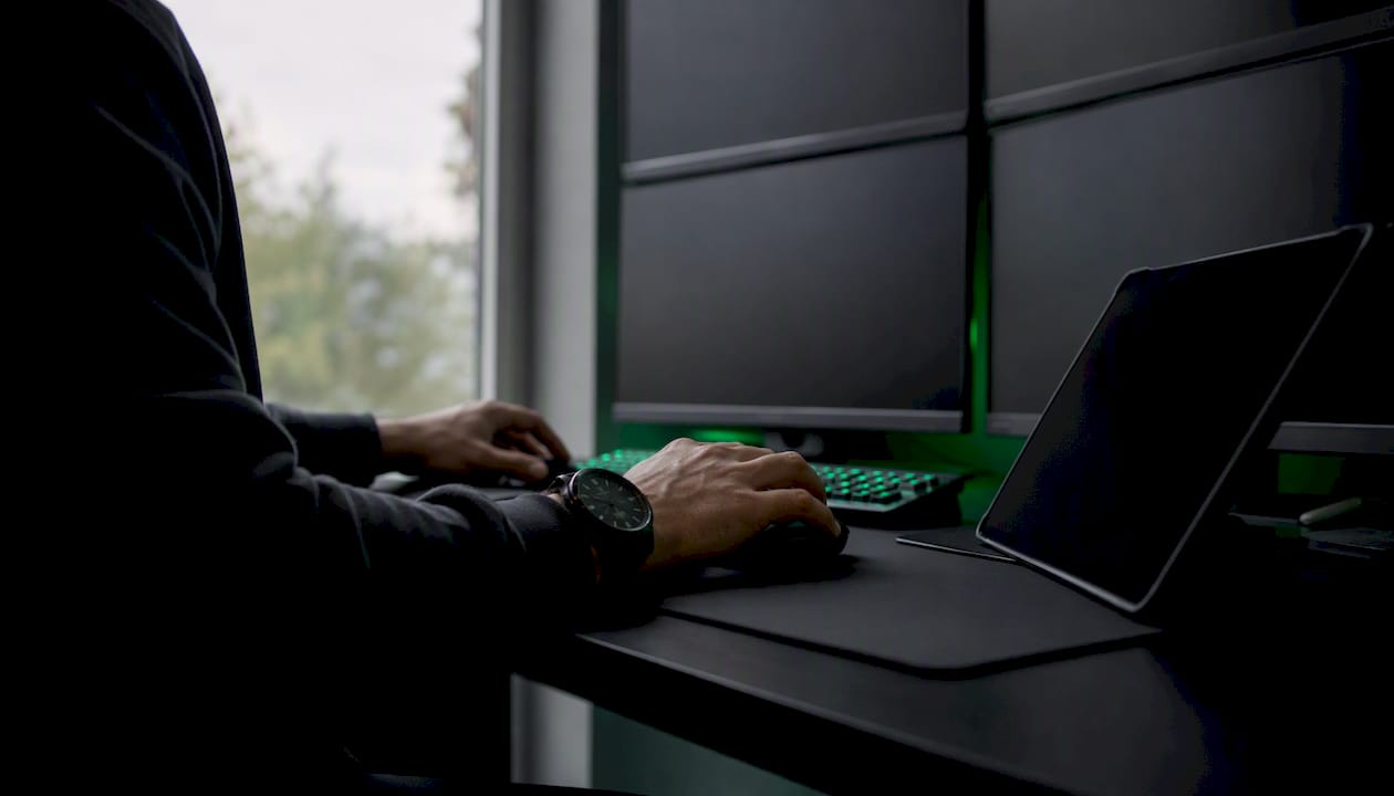 Kereskedő kezei sötét képernyők előtt egy trading munkaterületen