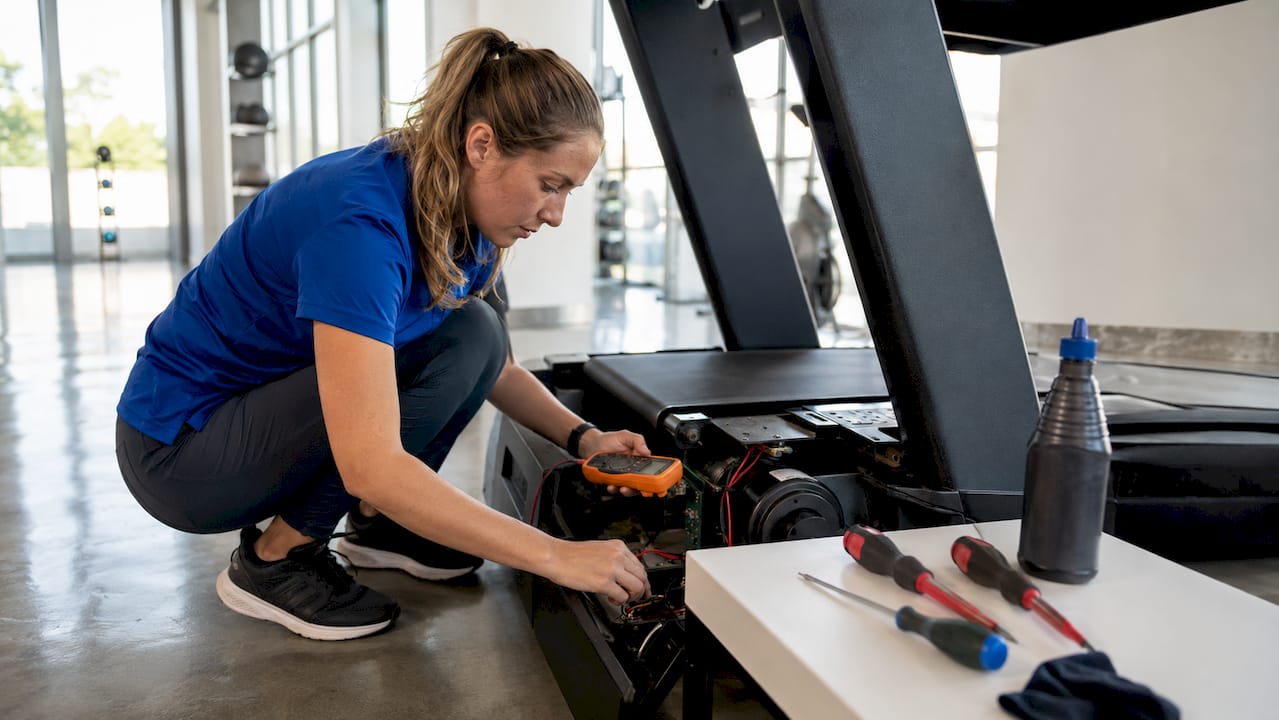 Technician inspecting treadmill motor closely