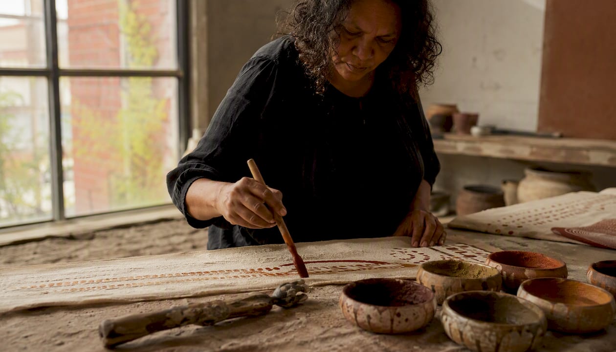 Hands painting Indigenous textile fabric